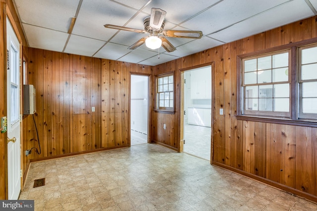 tiled spare room with wooden walls, ceiling fan, and a drop ceiling