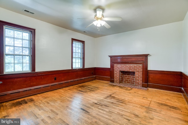 unfurnished living room featuring a fireplace, ceiling fan, hardwood / wood-style floors, and a baseboard heating unit