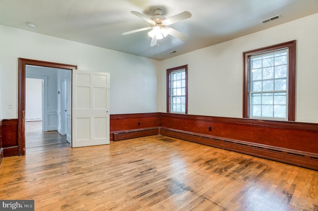 empty room with hardwood / wood-style flooring, a baseboard radiator, and ceiling fan