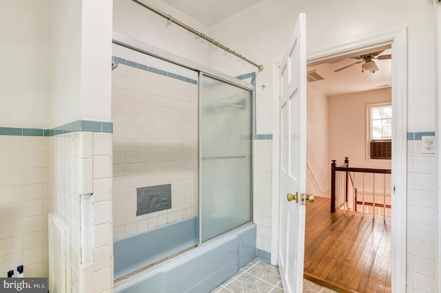 bathroom with tile walls, ceiling fan, bath / shower combo with glass door, and hardwood / wood-style floors