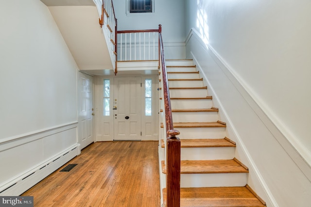 stairs with light hardwood / wood-style floors and baseboard heating