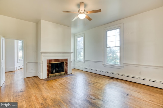 unfurnished living room featuring a fireplace, a baseboard radiator, light wood-type flooring, and ceiling fan