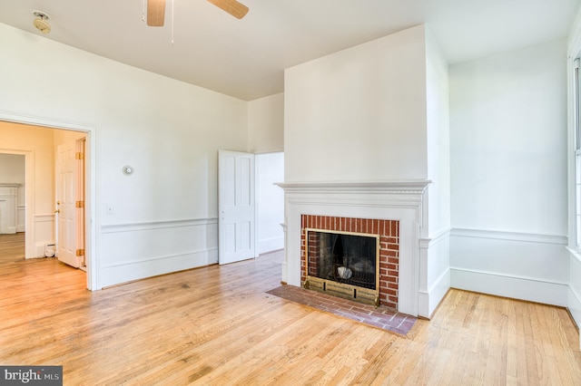 unfurnished living room with light hardwood / wood-style flooring, a brick fireplace, and ceiling fan