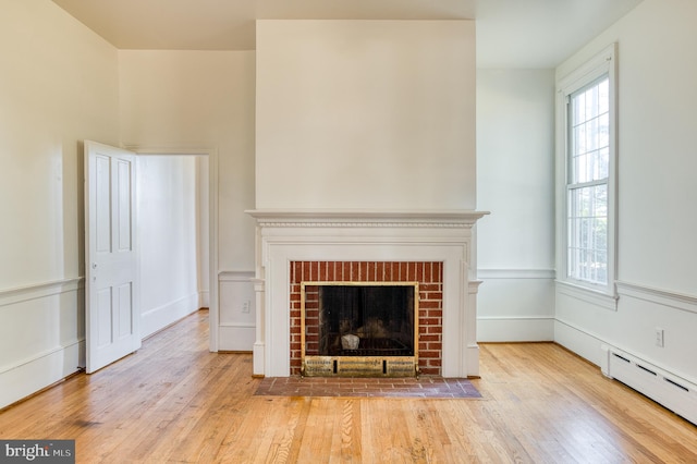 unfurnished living room with a baseboard radiator, a fireplace, and light wood-type flooring