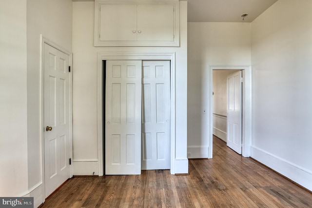 unfurnished bedroom with a closet and dark wood-type flooring