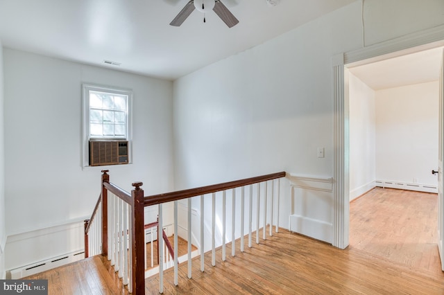 interior space with a baseboard heating unit, light hardwood / wood-style floors, and cooling unit