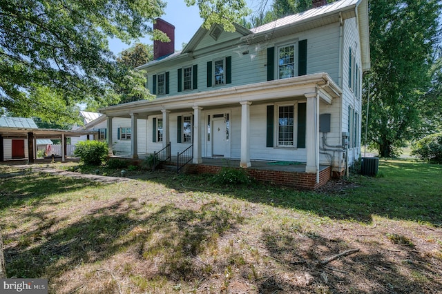 view of front facade with a front lawn, covered porch, a carport, and central AC unit