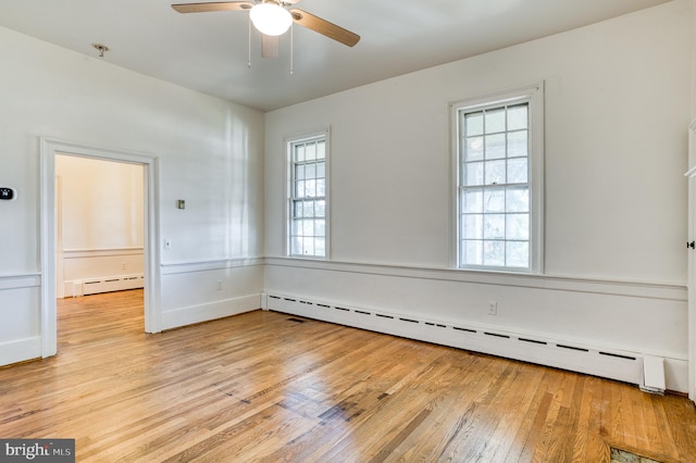 unfurnished room with light wood-type flooring, ceiling fan, a wealth of natural light, and a baseboard heating unit