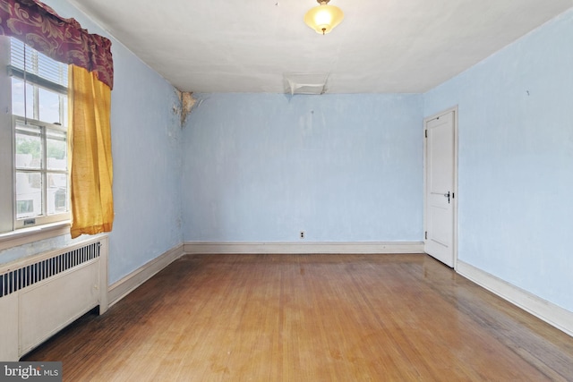 unfurnished room featuring hardwood / wood-style flooring and radiator heating unit