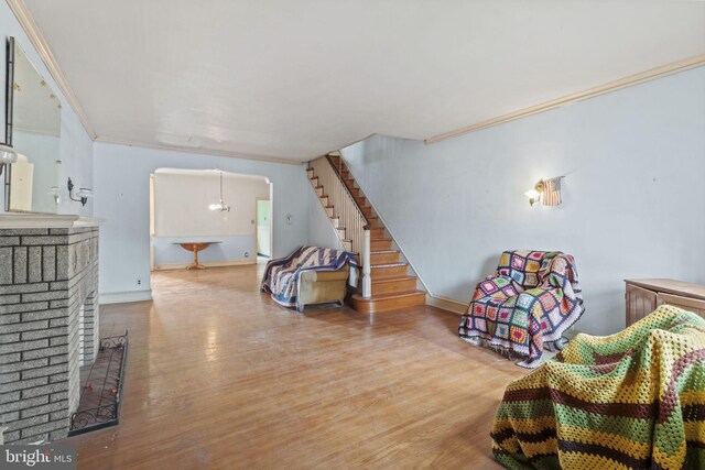 sitting room with a brick fireplace, wood-type flooring, and ornamental molding