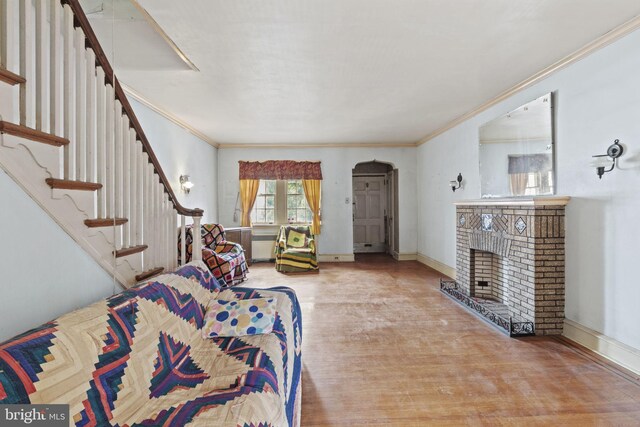 interior space featuring ornamental molding, a brick fireplace, and hardwood / wood-style flooring