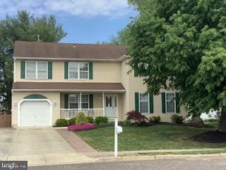 view of front of house with a porch, a garage, and a front lawn