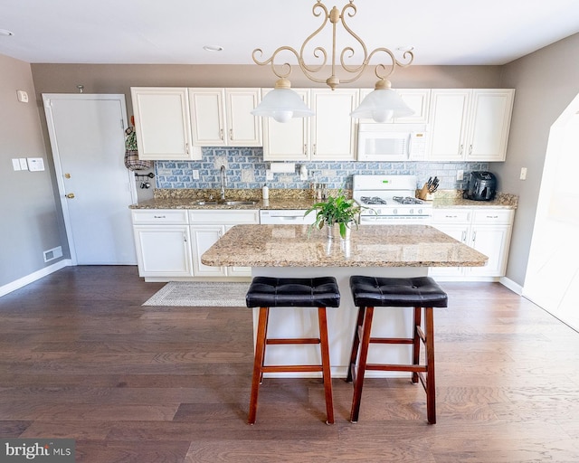 kitchen with white cabinetry, light stone countertops, sink, and white appliances