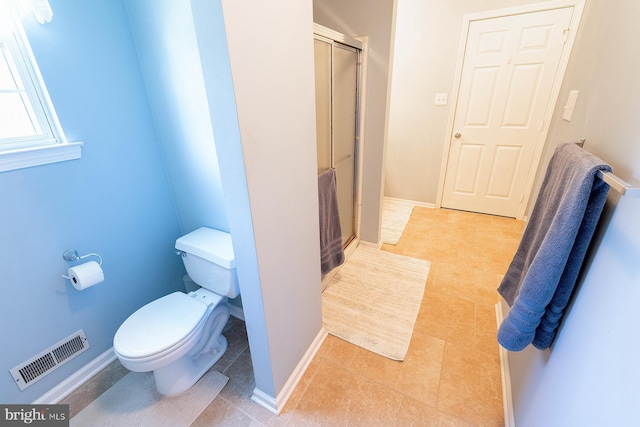 bathroom with tile patterned floors, toilet, and a shower with shower door