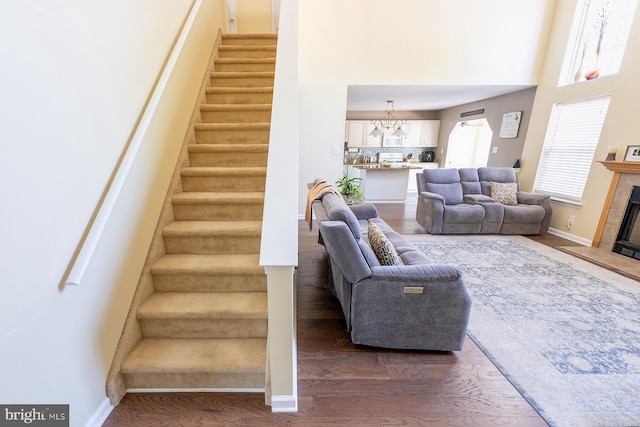 staircase featuring a chandelier, a fireplace, a healthy amount of sunlight, and hardwood / wood-style flooring