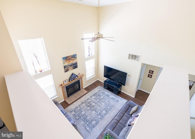 living room featuring ceiling fan, a high ceiling, and dark hardwood / wood-style floors