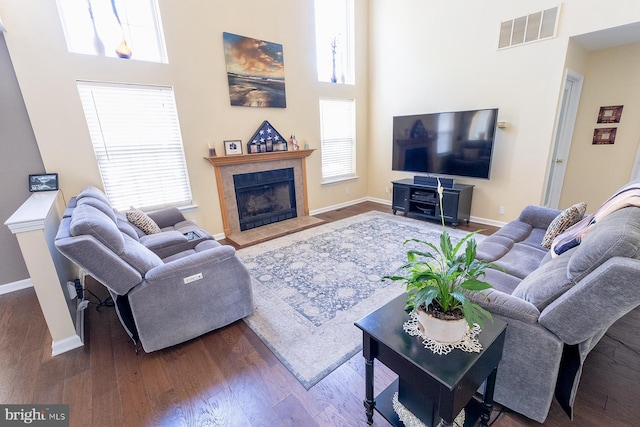 living room featuring hardwood / wood-style flooring, a healthy amount of sunlight, and a towering ceiling