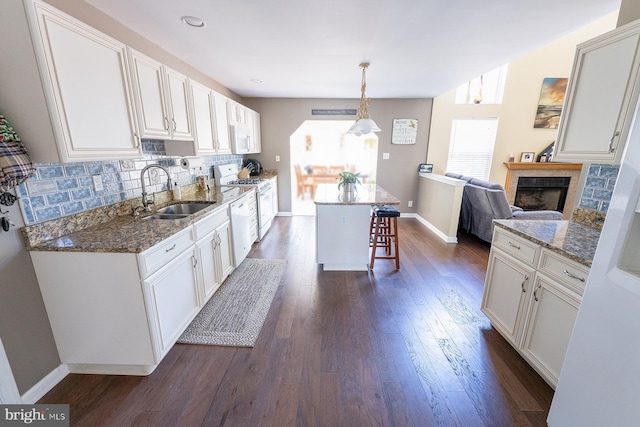 kitchen with a breakfast bar, white cabinetry, and sink