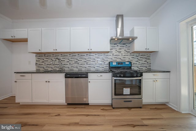 kitchen featuring decorative backsplash, white cabinetry, stainless steel appliances, and wall chimney exhaust hood