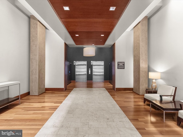 corridor featuring wood ceiling, light wood-type flooring, and elevator