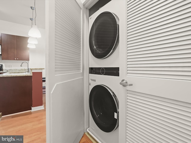 laundry area with stacked washing maching and dryer and sink