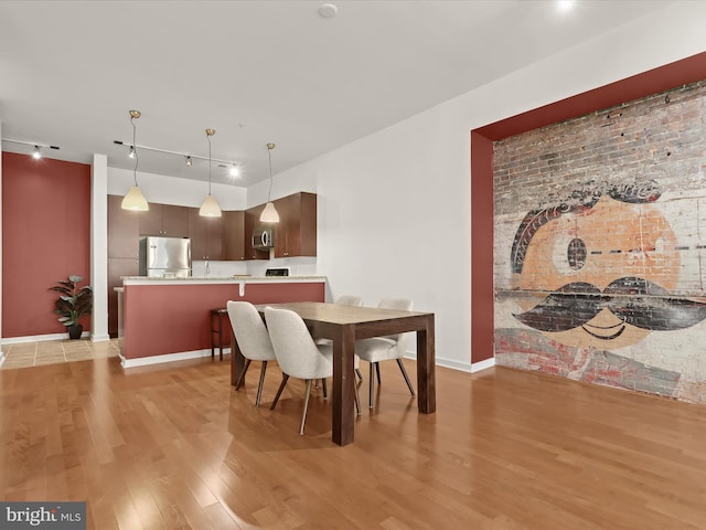 dining room with light hardwood / wood-style floors and track lighting