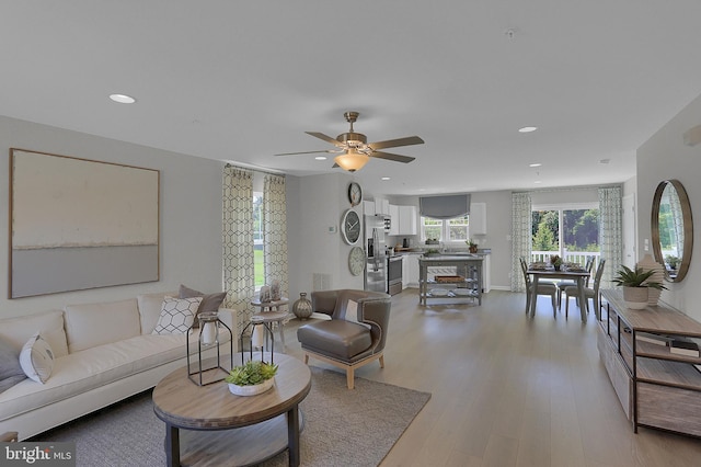 living room with ceiling fan and light wood-type flooring