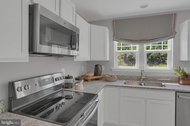 kitchen featuring white cabinets, stainless steel appliances, light stone countertops, and sink