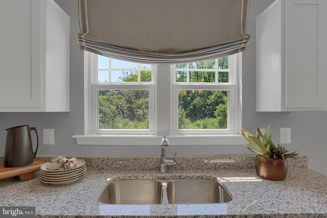 kitchen featuring sink, white cabinetry, and light stone countertops