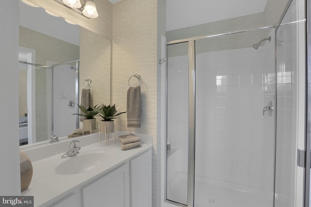 bathroom featuring a shower with door and vanity