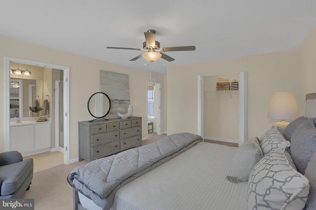 carpeted bedroom with sink, a closet, ceiling fan, and a walk in closet