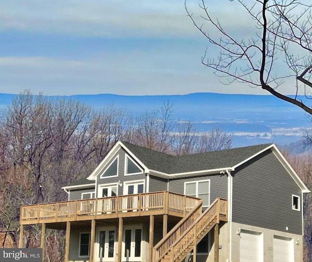 back of house with a deck with mountain view and a garage