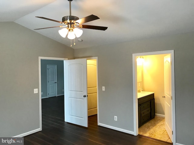 unfurnished bedroom with dark hardwood / wood-style flooring, connected bathroom, vaulted ceiling, and ceiling fan