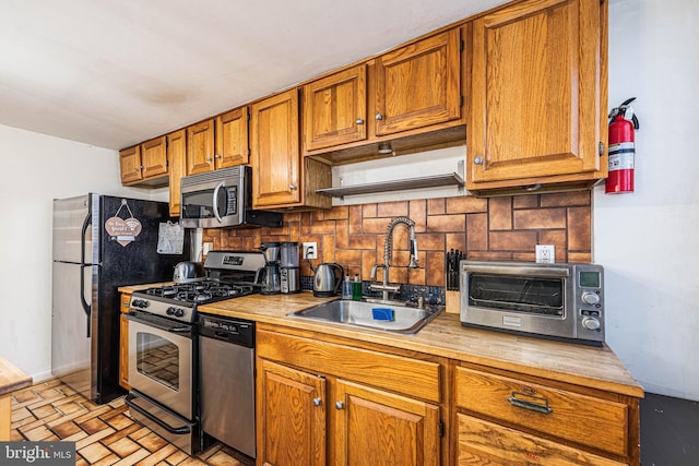 kitchen featuring decorative backsplash, stainless steel appliances, and sink