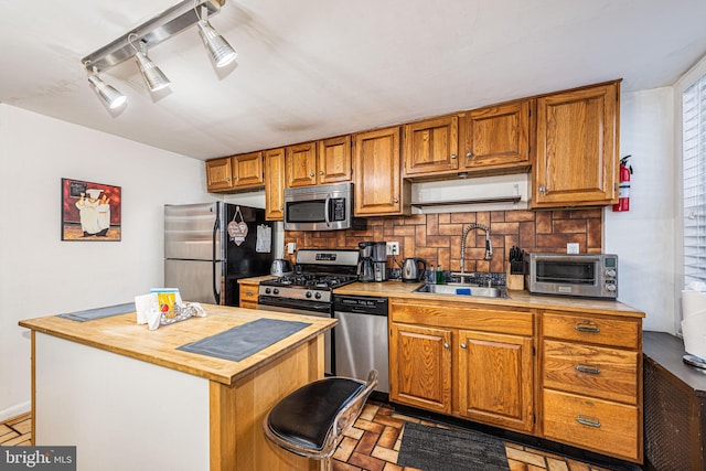 kitchen with light tile patterned floors, a kitchen island, stainless steel appliances, decorative backsplash, and sink