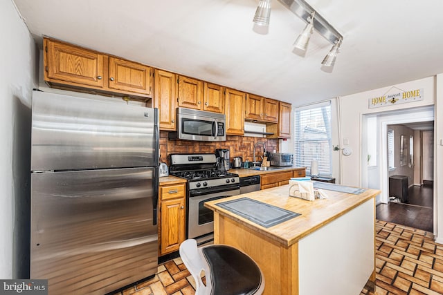 kitchen with light hardwood / wood-style flooring, backsplash, a center island, stainless steel appliances, and sink