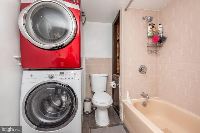 laundry area with stacked washer and clothes dryer, tile walls, and tile patterned flooring