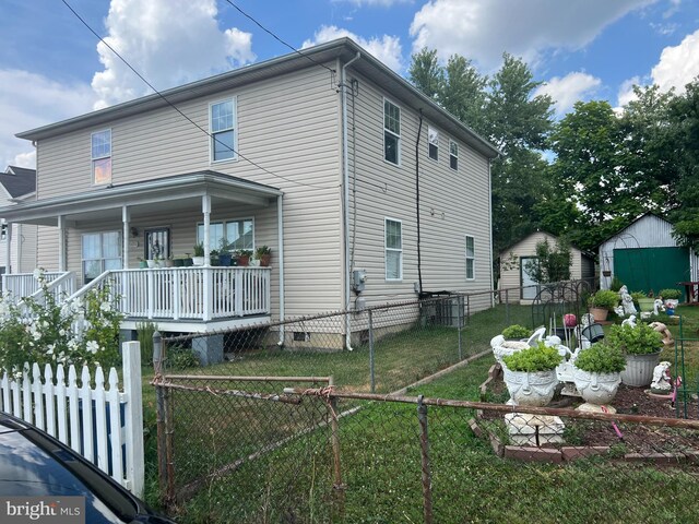 view of front of house with a front lawn, a storage unit, and covered porch