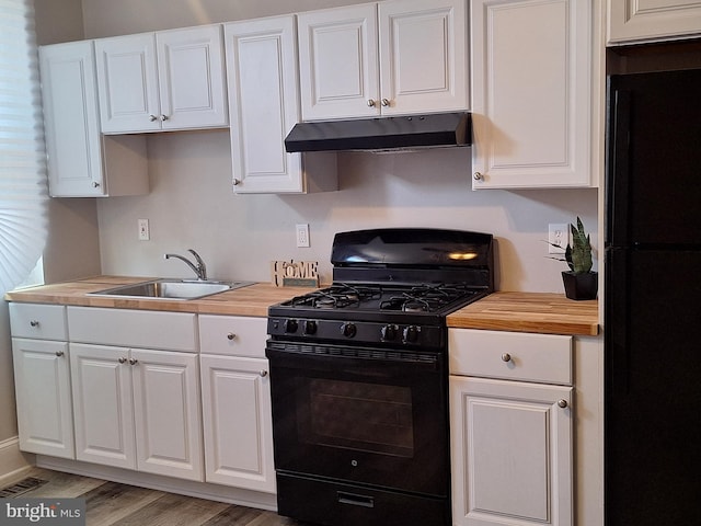 kitchen featuring wood counters, sink, black appliances, and white cabinets