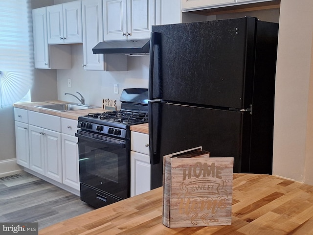 kitchen featuring wood counters, sink, black appliances, light hardwood / wood-style floors, and white cabinets