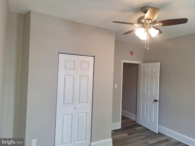 unfurnished bedroom featuring ceiling fan, dark hardwood / wood-style floors, and a closet