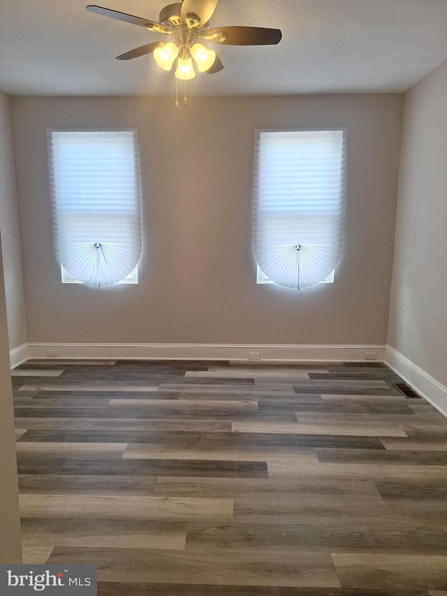 empty room with plenty of natural light, dark hardwood / wood-style floors, and ceiling fan