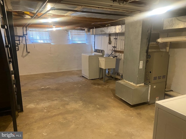 basement featuring separate washer and dryer, heating unit, and sink