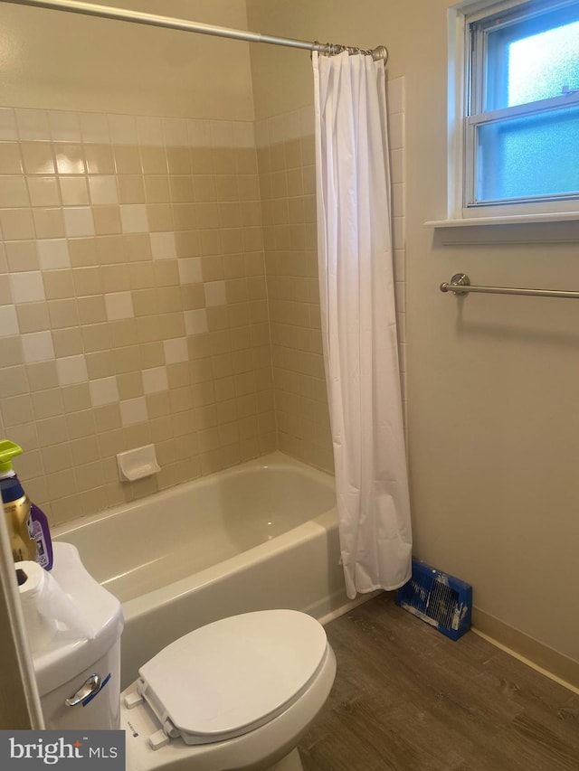 bathroom with hardwood / wood-style floors, toilet, and shower / tub combo with curtain