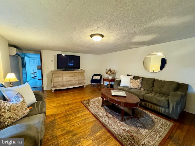 living room featuring a wall mounted air conditioner, a textured ceiling, and dark hardwood / wood-style flooring