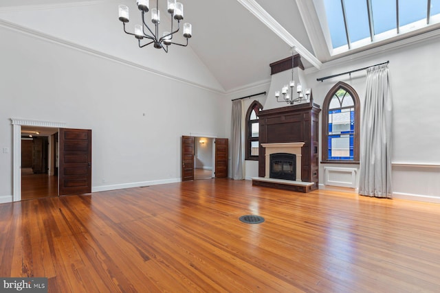 unfurnished living room featuring a chandelier, hardwood / wood-style flooring, high vaulted ceiling, and ornamental molding