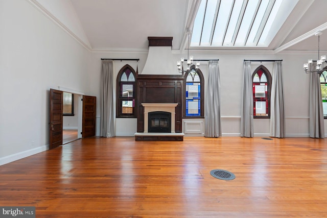 unfurnished living room featuring a chandelier, wood-type flooring, vaulted ceiling, and crown molding