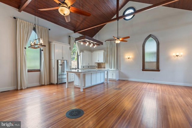 unfurnished living room with ceiling fan, beam ceiling, light hardwood / wood-style flooring, high vaulted ceiling, and wooden ceiling