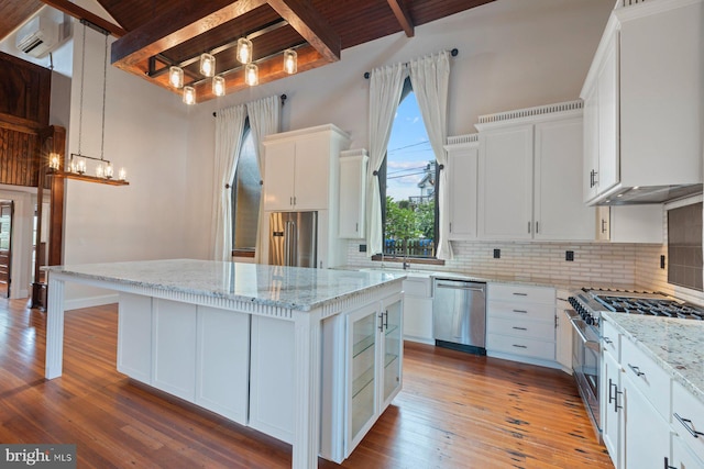 kitchen with premium appliances, a kitchen island, light stone countertops, and white cabinetry