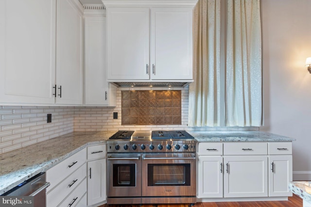 kitchen with white cabinetry, decorative backsplash, extractor fan, and appliances with stainless steel finishes